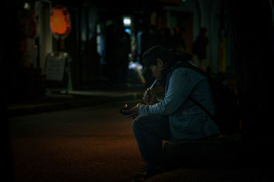 Side view of man playing guitar at music concert