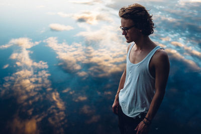 Side view of a man standing against cloud background