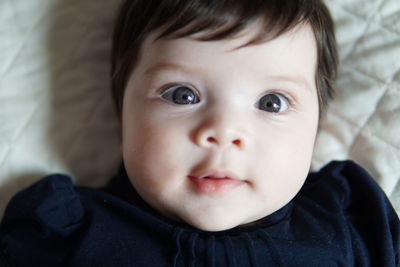 Close-up portrait of cute baby girl lying on bed