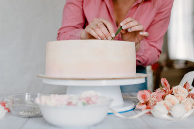 Female hand decorating pink flower wedding birthday cake
