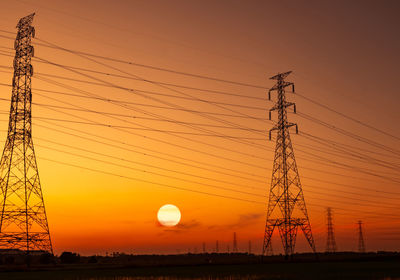 Low angle view of electricity pylon against sinset sky. transmission lines. 