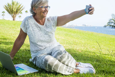 Young man using mobile phone in field