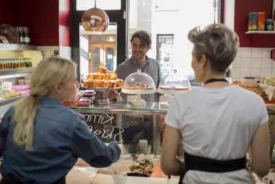 Rear view of saleswomen with customer standing at counter in supermarket