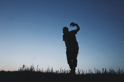 Silhouette man standing on field against clear sky