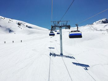 Ski lift over snow covered mountains against sky