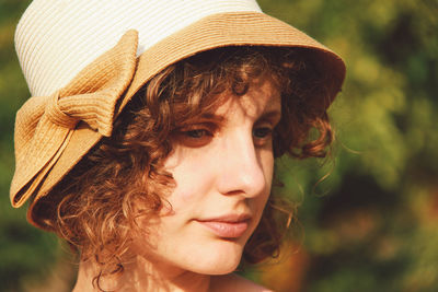 Close-up of beautiful young woman with brown curly hair wearing hat