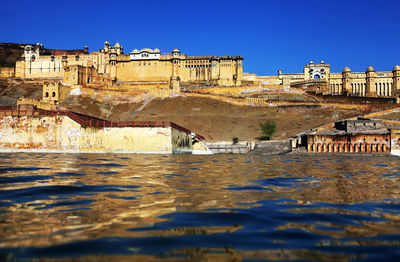 Amer fort on hill by maota lake against clear blue sky