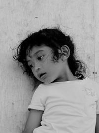 Portrait of cute girl looking away against wall at home