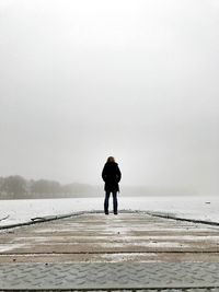 Rear view of woman standing on pier against sky