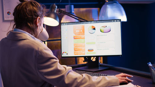 Rear view of woman using laptop on table