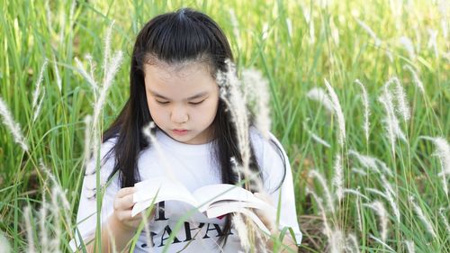 Close-up of girl holding plants in field