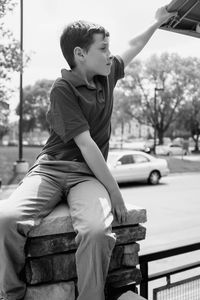 Boy sitting on railing in city