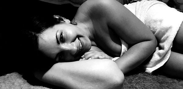 Close-up portrait of smiling woman lying on rug at home