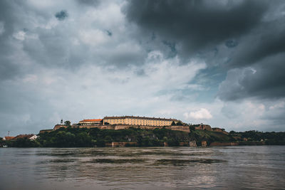 Buildings by river against sky