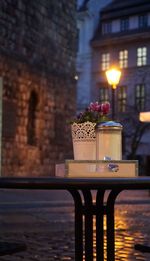 Illuminated restaurant by glass building at dusk