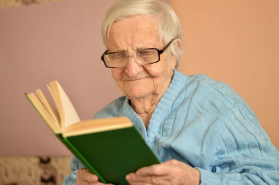 Old senior woman 90 years old holding open paper book in hands, reading best seller novel concept