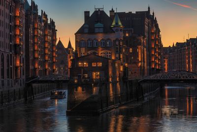 Canal passing through city buildings at sunset