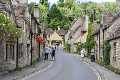 Rear view of people walking on road amidst buildings