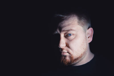 Close-up portrait of serious man against black background