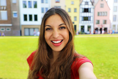 Portrait of smiling young woman standing against buildings
