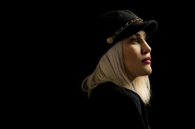 Portrait of woman looking away against black background