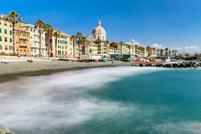 View of canal and buildings against blue sky