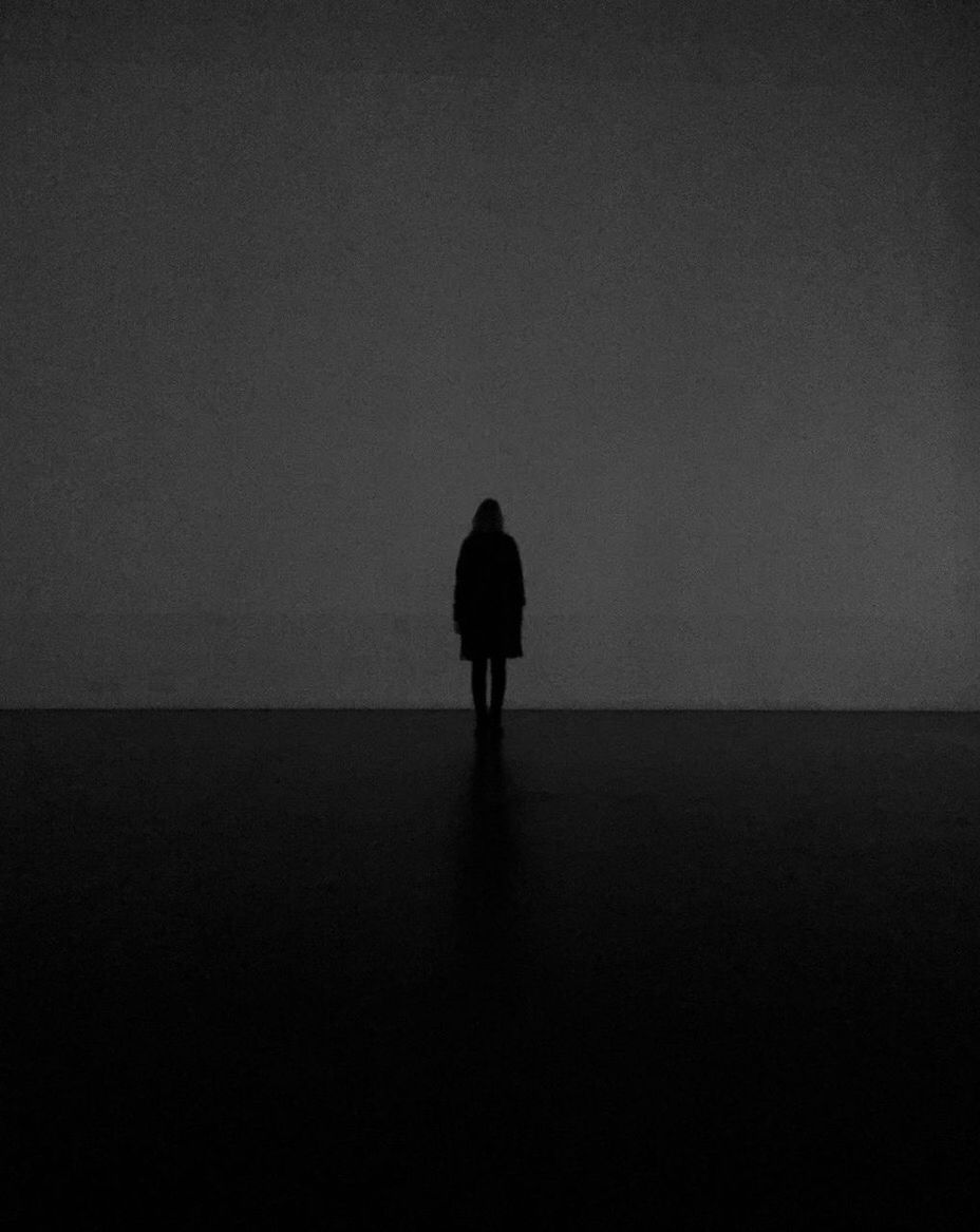 REAR VIEW OF SILHOUETTE WOMAN WALKING IN DARK ROOM