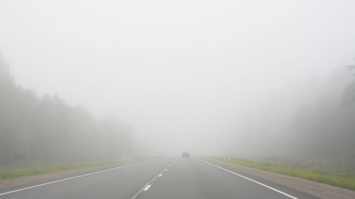 Empty road against clear sky in foggy weather