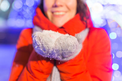 Portrait of smiling woman holding snow during winter