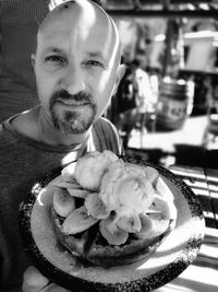 Portrait of man holding ice cream on table