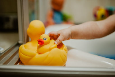 Cropped hand of child holding rubber duck in bathroom