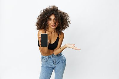 Portrait of young woman standing against white background