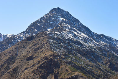 Low angle view of snowcapped mountains against clear blue sky