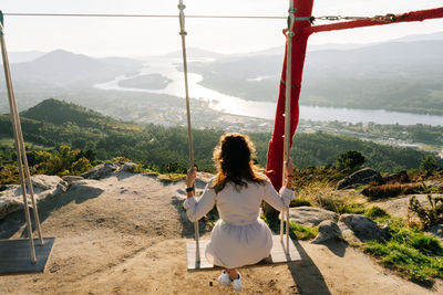 Rear view of woman swinging on mountain