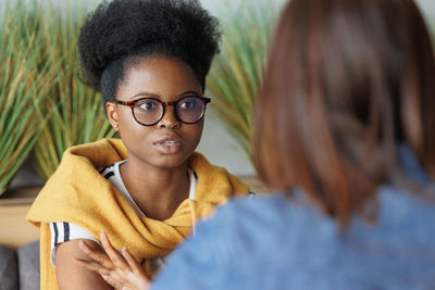 Woman wearing eyeglasses talking with friend