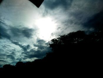 Low angle view of silhouette trees against storm clouds