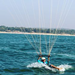 Man kiteboarding in sea against sky