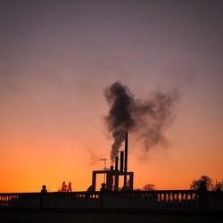 Smoke emitting from factory against sky during sunset