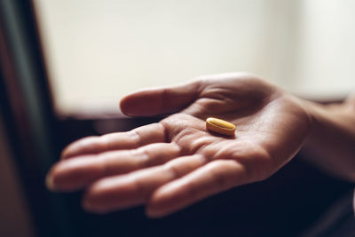 From above of crop palm of anonymous person demonstrating yellow vitamin pill for healthy lifestyle concept