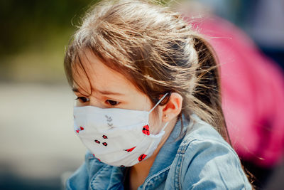 Close-up of cute girl looking down while wearing mask