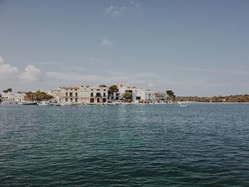 Buildings by sea against sky
