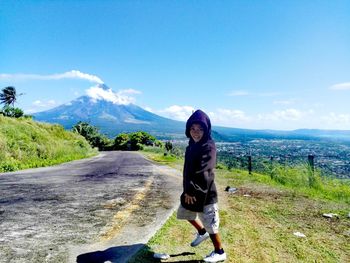 Portrait of boy walking on field against sky