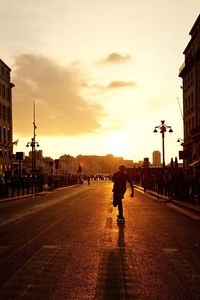 People walking on road in city at sunset