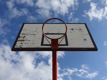 Basketball hoop on an outdoor court with sky and clouds background
