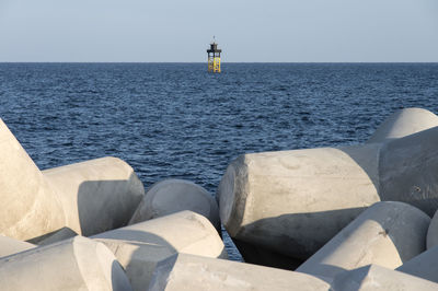 Mid-distance view of beacon in sea against clear sky