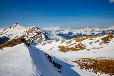 Scenic view of snowcapped mountains against blue sky