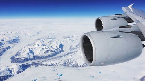 Airplane flying over snow covered landscape