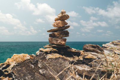 Stack of rocks by sea against sky