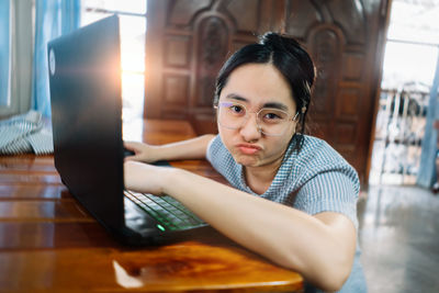 Portrait of woman using laptop while sitting on table