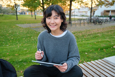 Portrait of young woman sitting on field